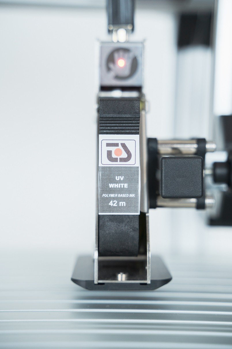 Malá a jednoduchá cartridge tiskárna TS Electronics Zlín s polymerním bílým inkoustem, který se po aktivaci UV LED světlem změní na zesíťovaný plast s velkou odolností na otěr a chemii.